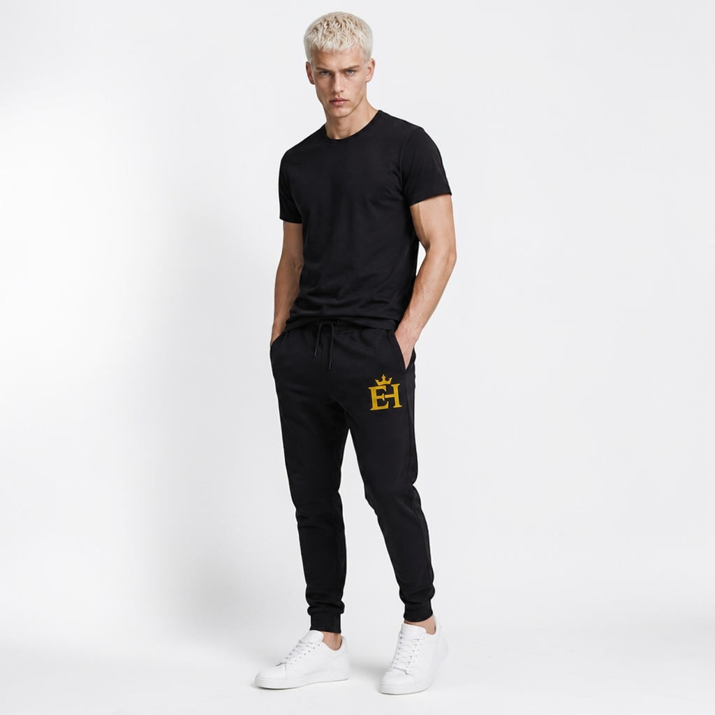 Man styling black EH Crown Signature Premium Sweatpants with gold embroidery in a clean streetwear look.