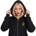 Female model wearing the INSPIRED Sovereign Zip Hoodie in black with gold infinity-trident emblem, hood up.
